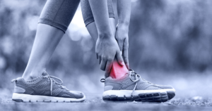 Person holding their ankle in apparent pain while outdoor, with the ankle area highlighted in red to indicate injury or discomfort, po ibly a candidate for Chamber Treatment.